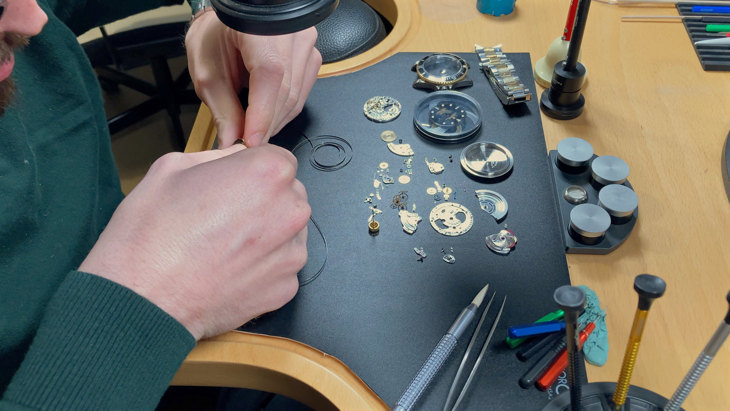 Horloger en pleine restauration d’une montre automatique démontée, réparation et révision du mouvement
