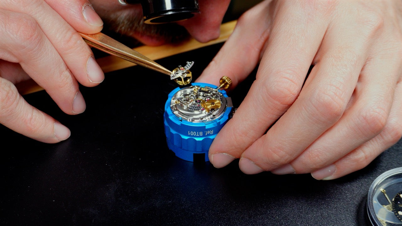 Horloger intervenant sur une montre démontée lors d’une réparation et révision de montre ancienne ou automatique